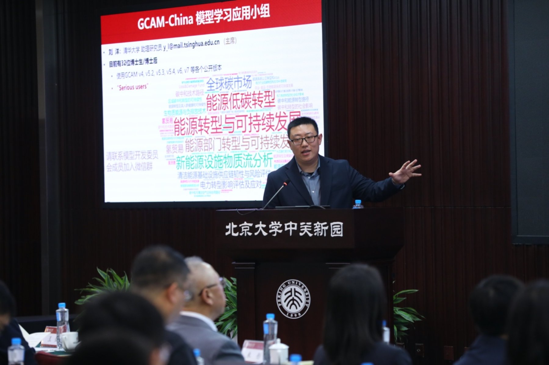 A person standing at a podium with a screen behind him
Description automatically generated